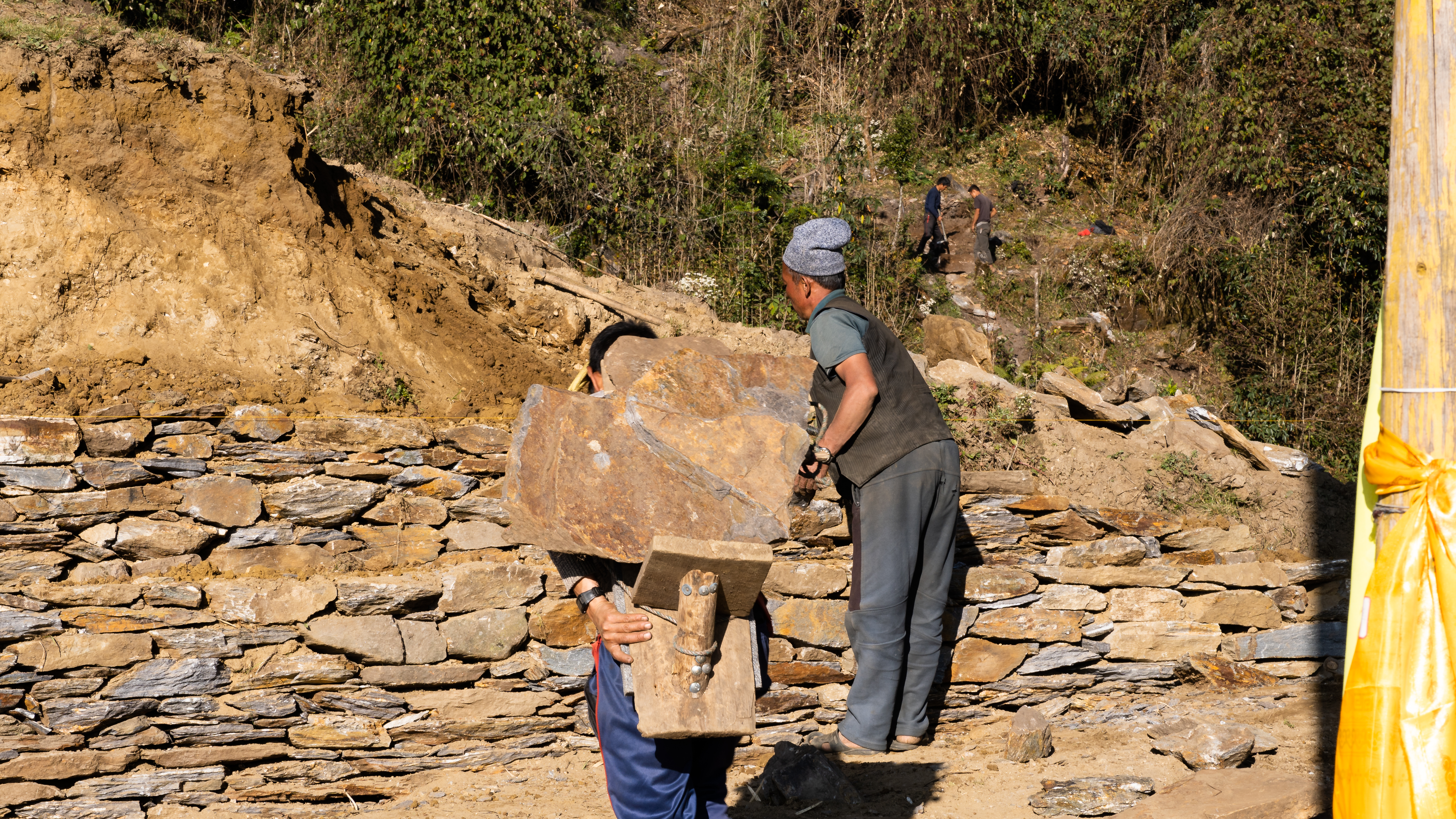 #width=100%;max-width=1000px;margin-left=auto;margin-right=auto; The building process: In the background, men mine surface rock brittle enough to break. Others carry it to the site, where it is hewn into building blocks and stacked.
